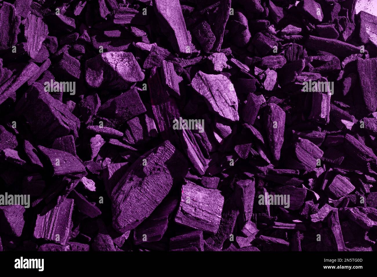 Natürliche schwarze Holzkohle mit violettem Farbton. Industriekohle. Schwarzer Kohlehaufen, schwarze Farbe, Kohleteile unterschiedlicher Größe. Stockfoto