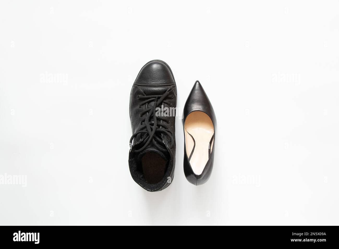 Männerstiefel und klassische schwarze Damenschuhe auf weißem Hintergrund, verschiedene Schuhe, Mode und Style Stockfoto