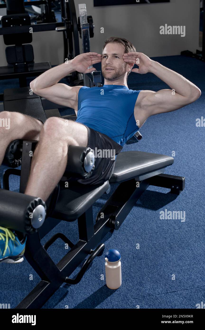 Ein erwachsener Mann, der auf einer Bank sitzt, um seine Bauchmuskeln zu trainieren. Bayern, Deutschland Stockfoto