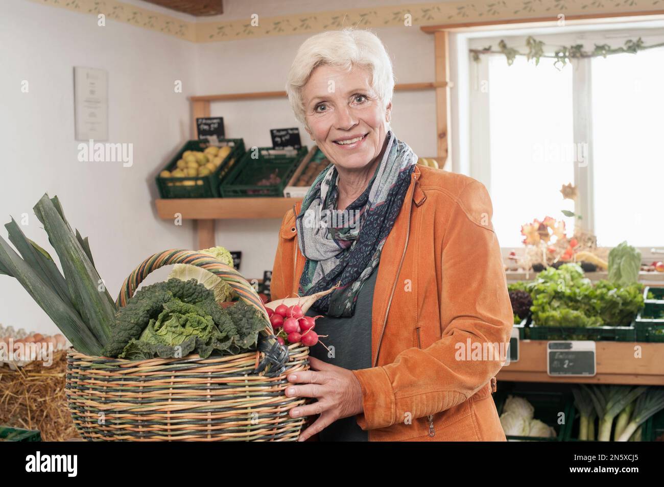 Porträt einer reifen Frau, die Gemüse auf dem Bauernhof kauft und lächelt, Bayern Stockfoto