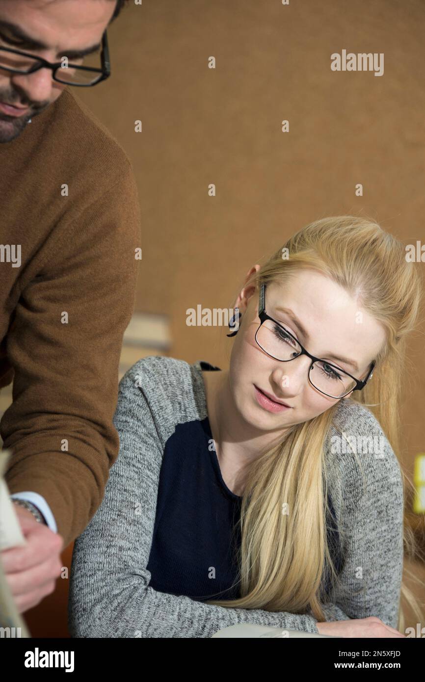 Lehrer, der der Schülerschule in Bayern, Deutschland, etwas im Buch erklärt Stockfoto