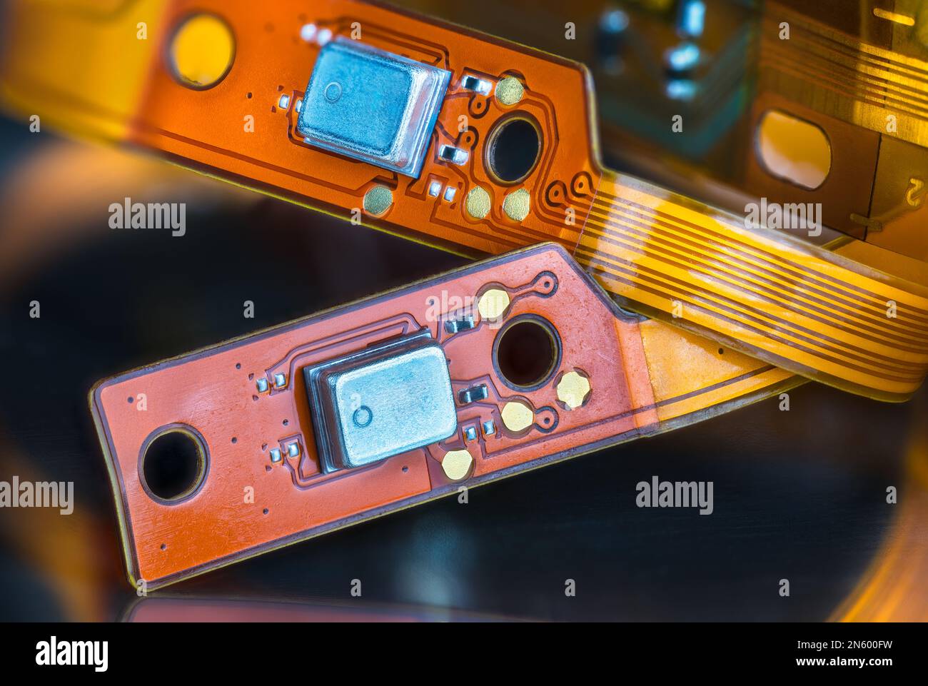 Wunderschöne flexible elektronische gedruckte Schaltungen auf gelben und orangefarbenen Streifen auf schwarzem, verschwommenem Hintergrund. Nahaufnahme von biegsamen Leiterplatten oder kleinen Bauteilen. Stockfoto