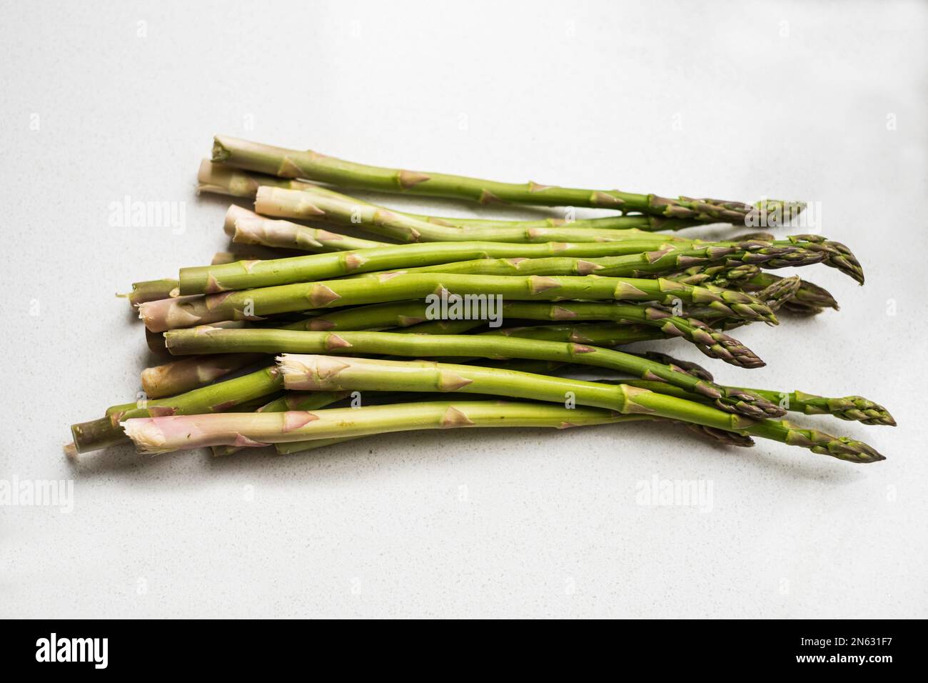 Ein Bündel frischer roher Spargel, der auf einer weißen Arbeitsfläche liegt. USA. Stockfoto