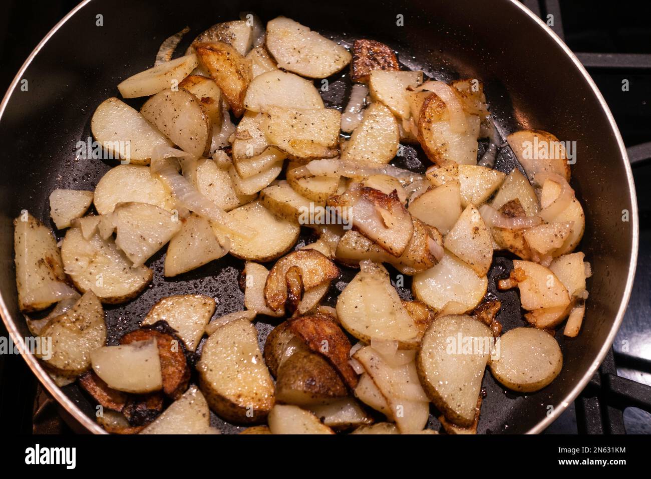 Eine Nahaufnahme von Bratkartoffeln und Zwiebeln in einer Pfanne auf einem Herd. USA. Stockfoto