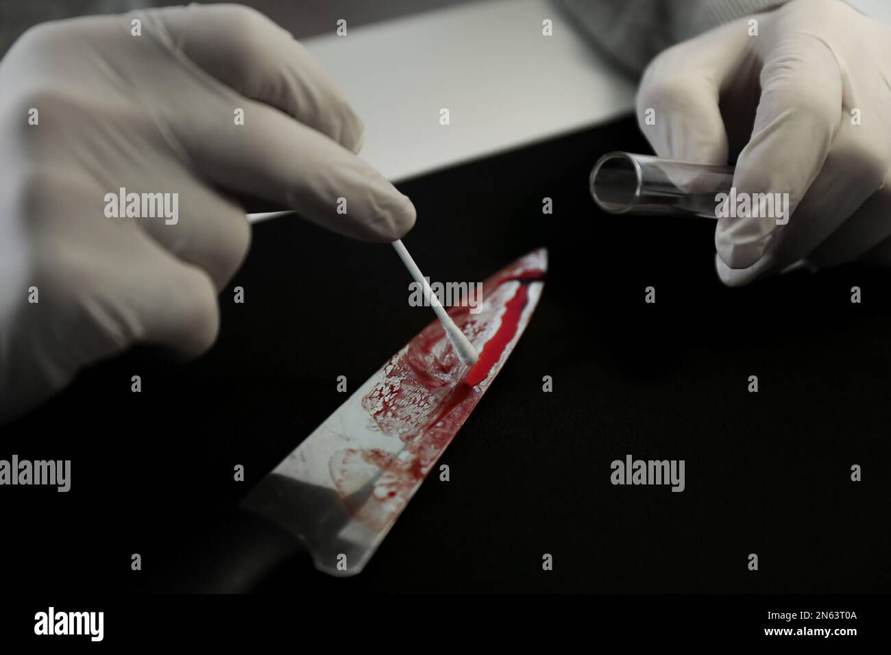 Detective nimmt DNA-Probe von Blut vom Messer am Tisch, Nahaufnahme Stockfoto