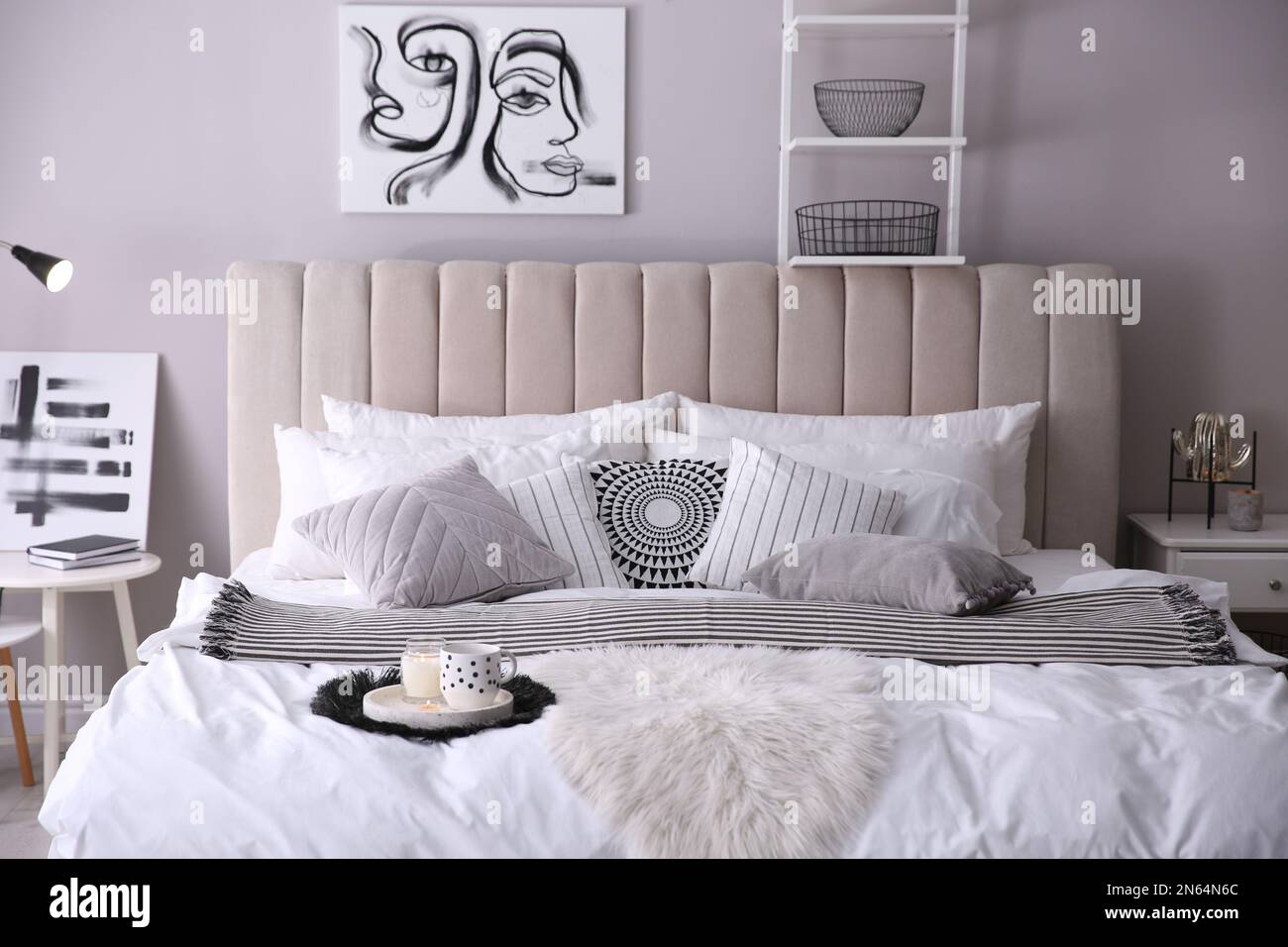 Gemütliche Innenausstattung des Schlafzimmers mit Kissen und gestreifter Decke Stockfoto