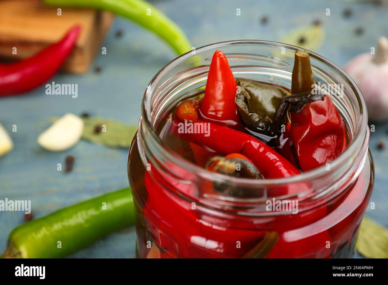 Glas mit eingelegtem Chili auf hellblauem Tisch, Nahaufnahme Stockfoto