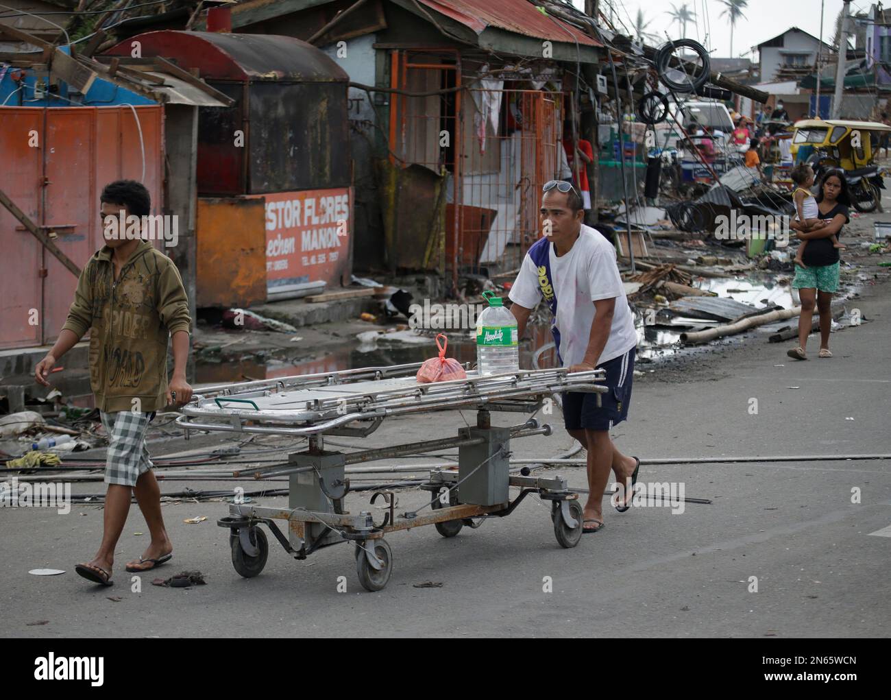 Typhoon survivors use a hospital bed to load their items, Sunday Nov. 17, 2013 at typhoon-ravaged Tacloban city, Leyte province in central Philippines. Typhoon Haiyan, one of the most powerful typhoons ever recorded, slammed into central Philippine provinces on Nov. 8, leaving a wide swath of destruction and thousands of people dead. (AP Photo/Bullit Marquez) Stockfoto