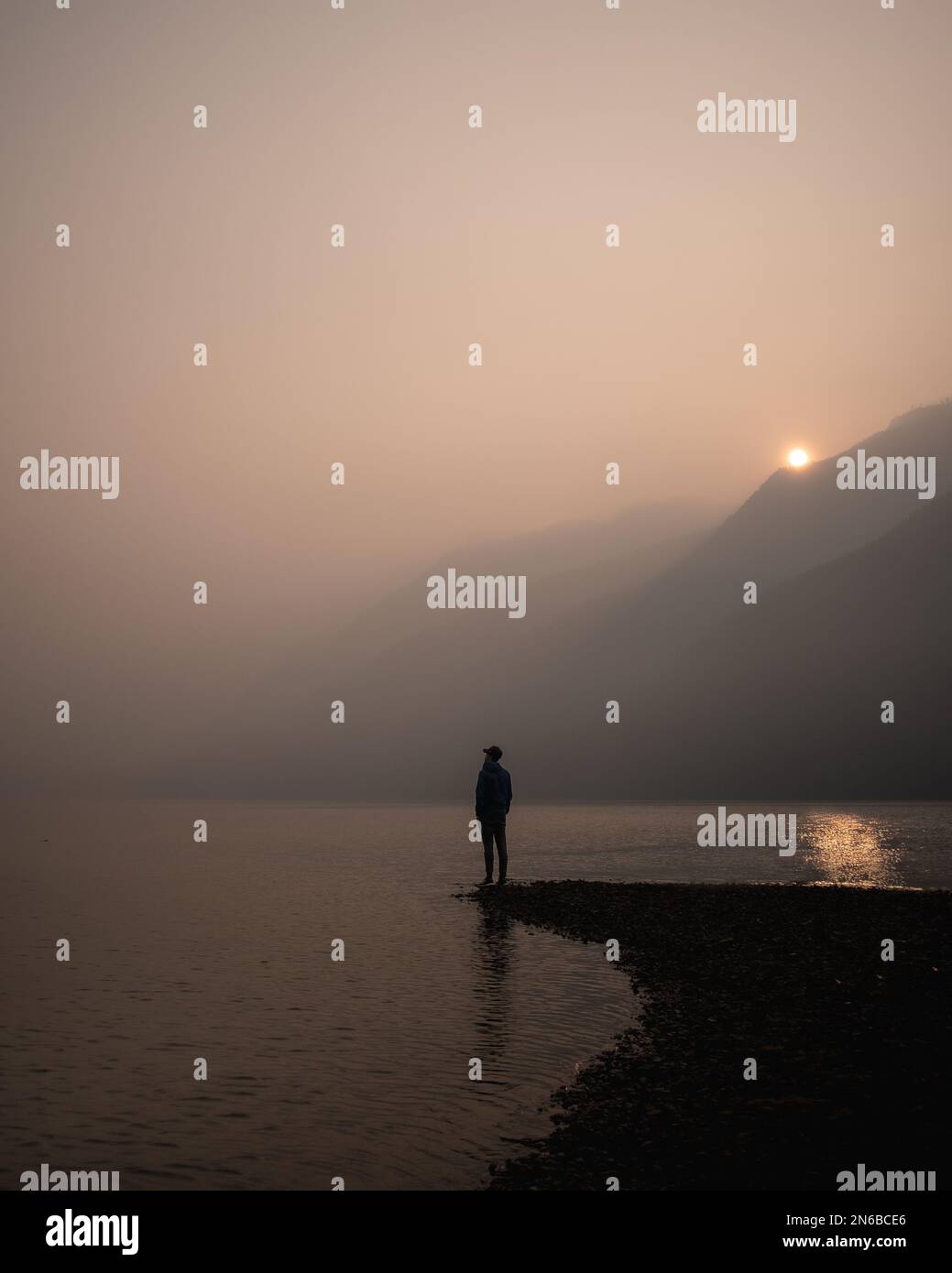 Silhouette eines Mannes am See während eines rauchigen Sonnenaufgangs Stockfoto