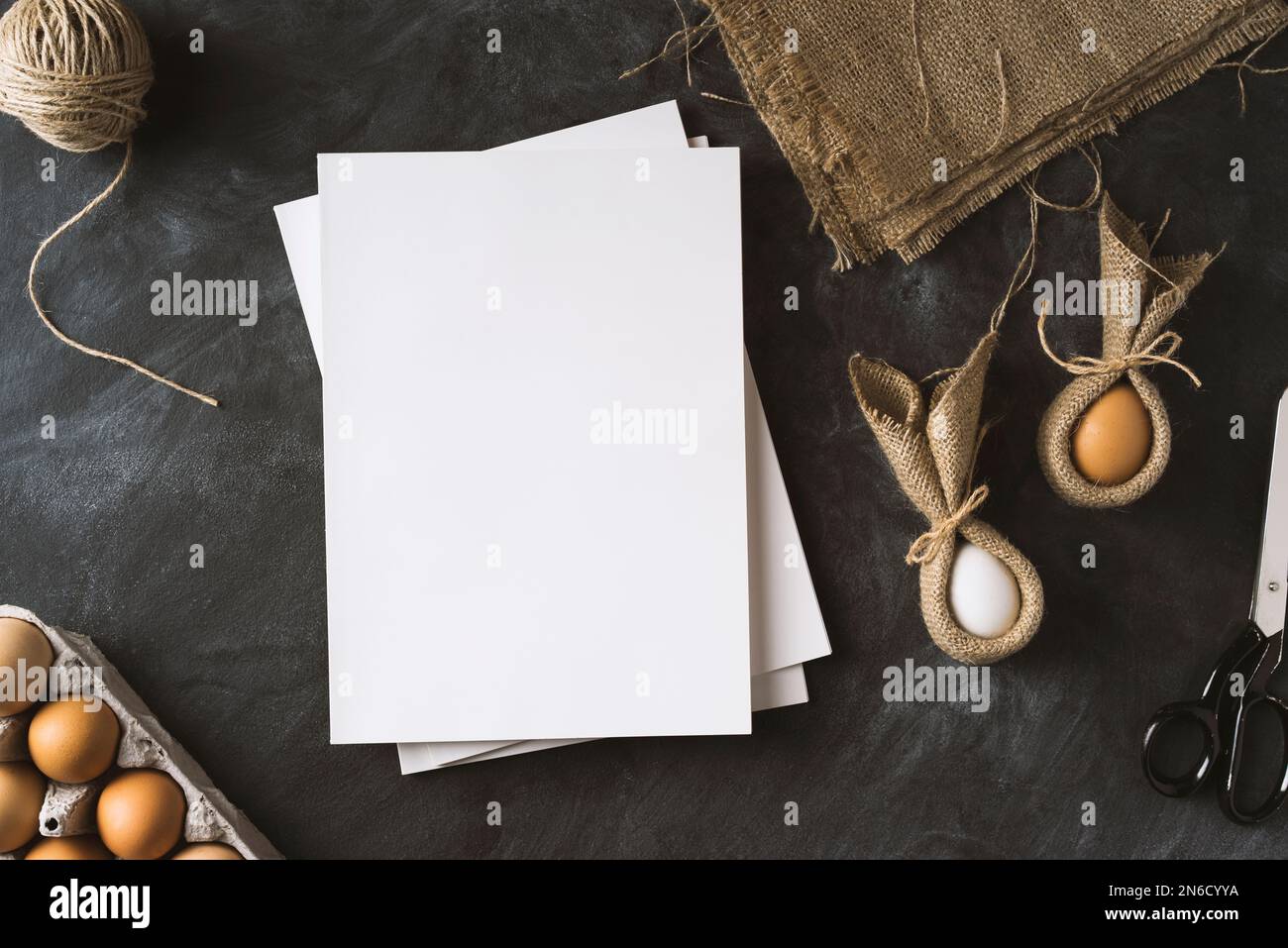 Ostervorbereitungen. Tischaufnahme mit weißen, unbeschrifteten Titelzeitschriften und osterhäschen-Eiern. Stockfoto