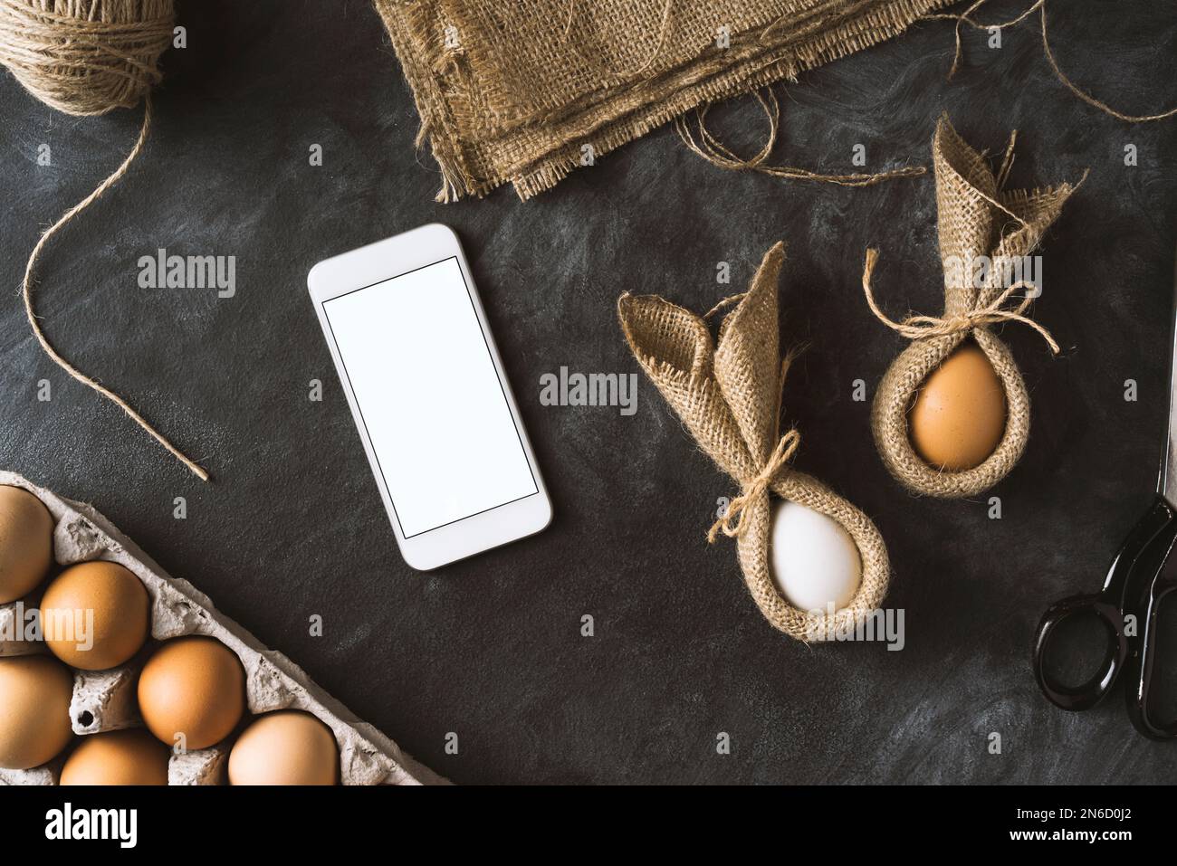 Ostervorbereitungen. Tischaufnahme mit Smartphone und osterhäschen-Eiern. Stockfoto