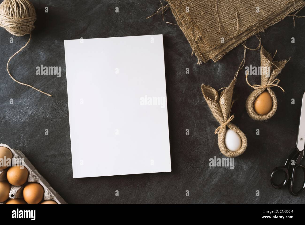 Ostervorbereitungen. Tischaufnahme mit weißem, unbeschriftetem Cover-Magazin und osterhäschen-Eiern. Stockfoto