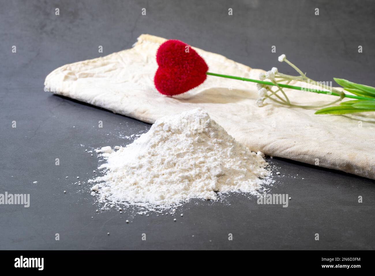 Hausgemachtes Allzweckbrot mit Mehlhaufen auf schwarzem Hintergrund. Stockfoto