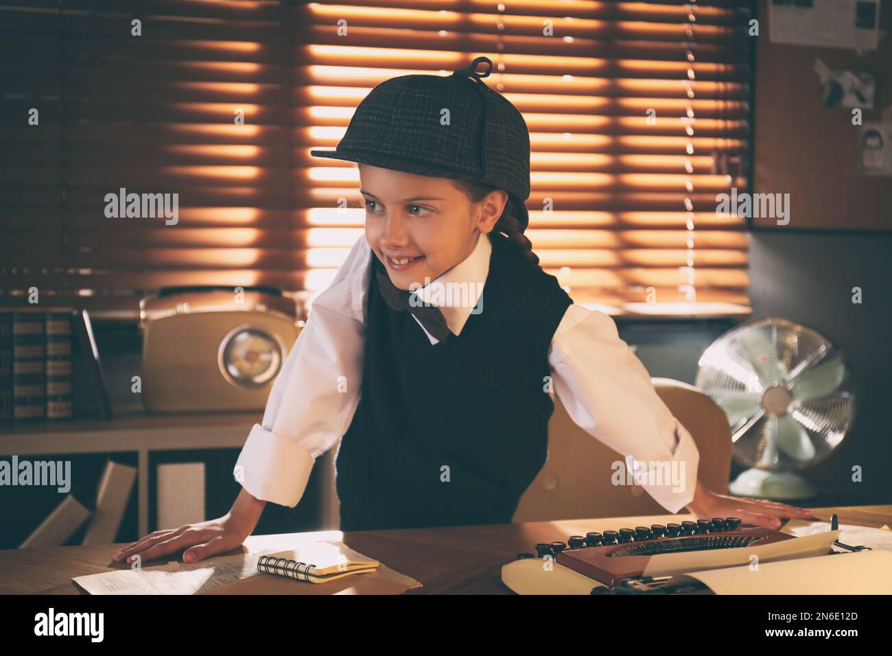 Süßer kleiner Detective am Tisch im Büro Stockfoto