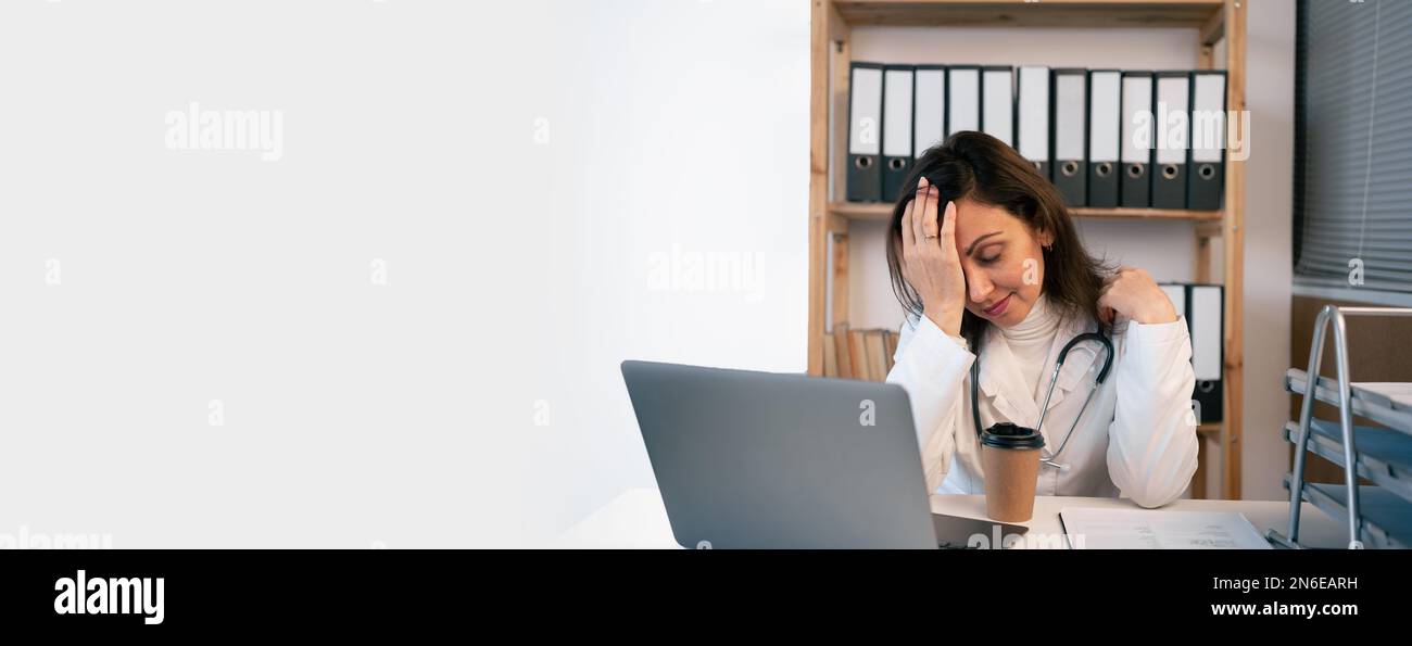 Unzufriedener, müder Arzt, der Computer benutzt und eine E-Mail in der Arztpraxis liest. Überarbeiteter Kopfschmerzarzt in der modernen Praxis, Medizin Stockfoto