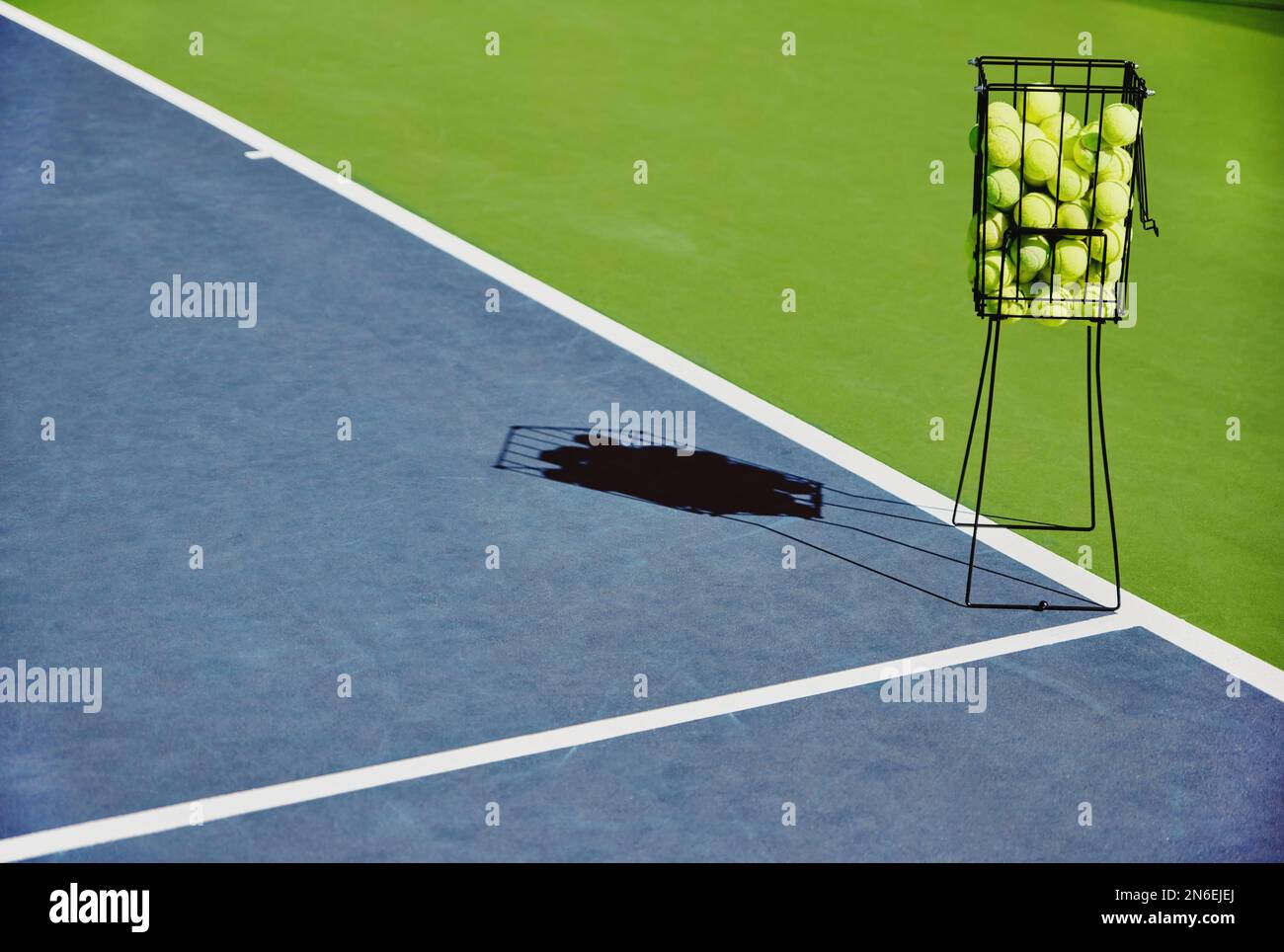 Tennis, Sportbälle und Sportausrüstung auf einem Trainingsplatz im Freien ohne Leute. Sport-, Fitness- und Trainingsgeräte im Schatten für Stockfoto