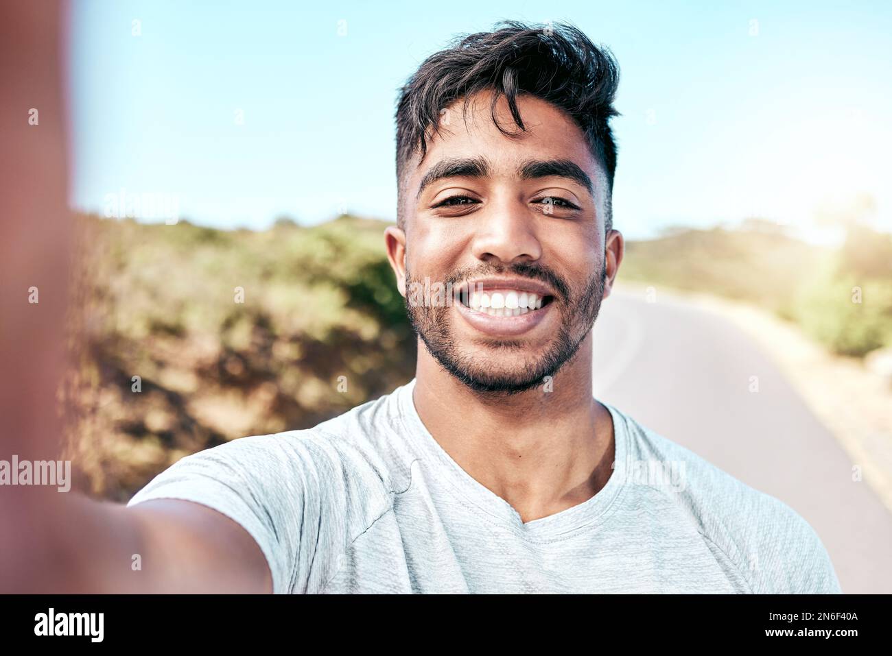 Ein Mann aus dem Mischrennsport macht beim Laufen ein Selfie. Attraktiver hispanischer männlicher Athlet, der während des Trainings lächelt, um ein Selbstporträtfoto zu machen Stockfoto