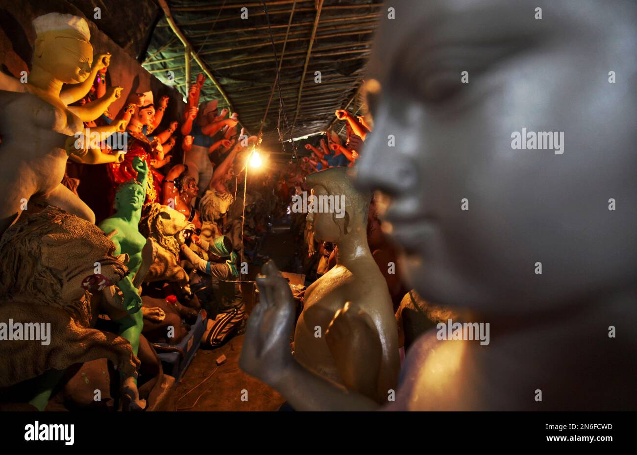 An Indian artist adjusts an electric bulb as he prepares idols of Hindu