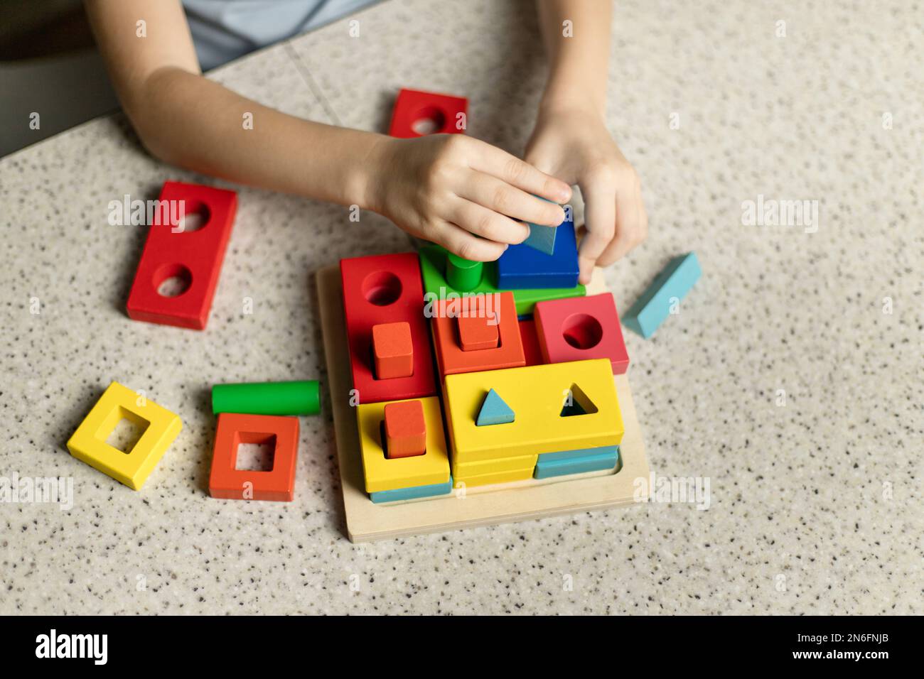 Ein Kind spielt ein pädagogisches Puzzle aus umweltfreundlichem Holz Stockfoto