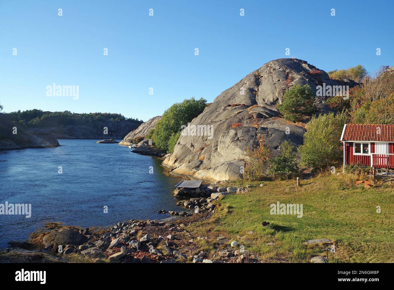 Abgerundete Granitfelsen, flache Buchten und kleine Hütte am Ufer eines Fjords, Inselküste, Bohulaen, Schweden Stockfoto