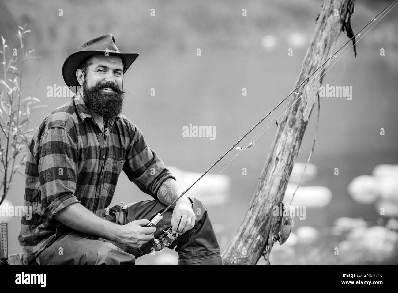 Mann beim Angeln. Allein sitzen während des Angelprozesses in der Nähe des Sees. Hobby und sportliche Aktivitäten. Fischer mit Rute und Fisch. Pothunter. Fischer Stockfoto