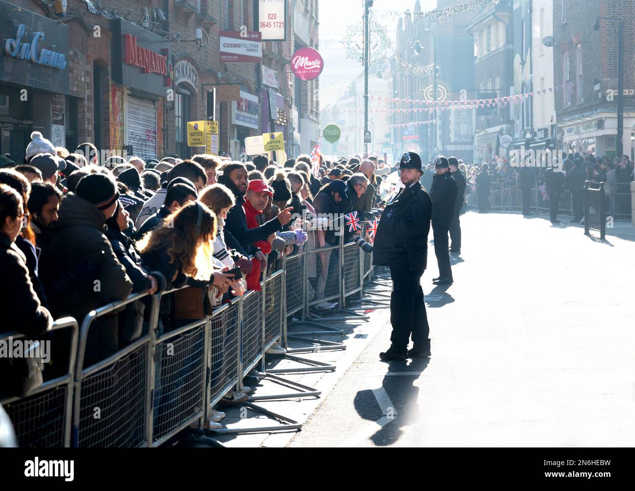 London, England, Großbritannien. Menschenmassen und Polizei in Brick Lane warten auf die Ankunft von König Charles und Camilla für einen Besuch der Moschee. 8. Februar 2023 Stockfoto