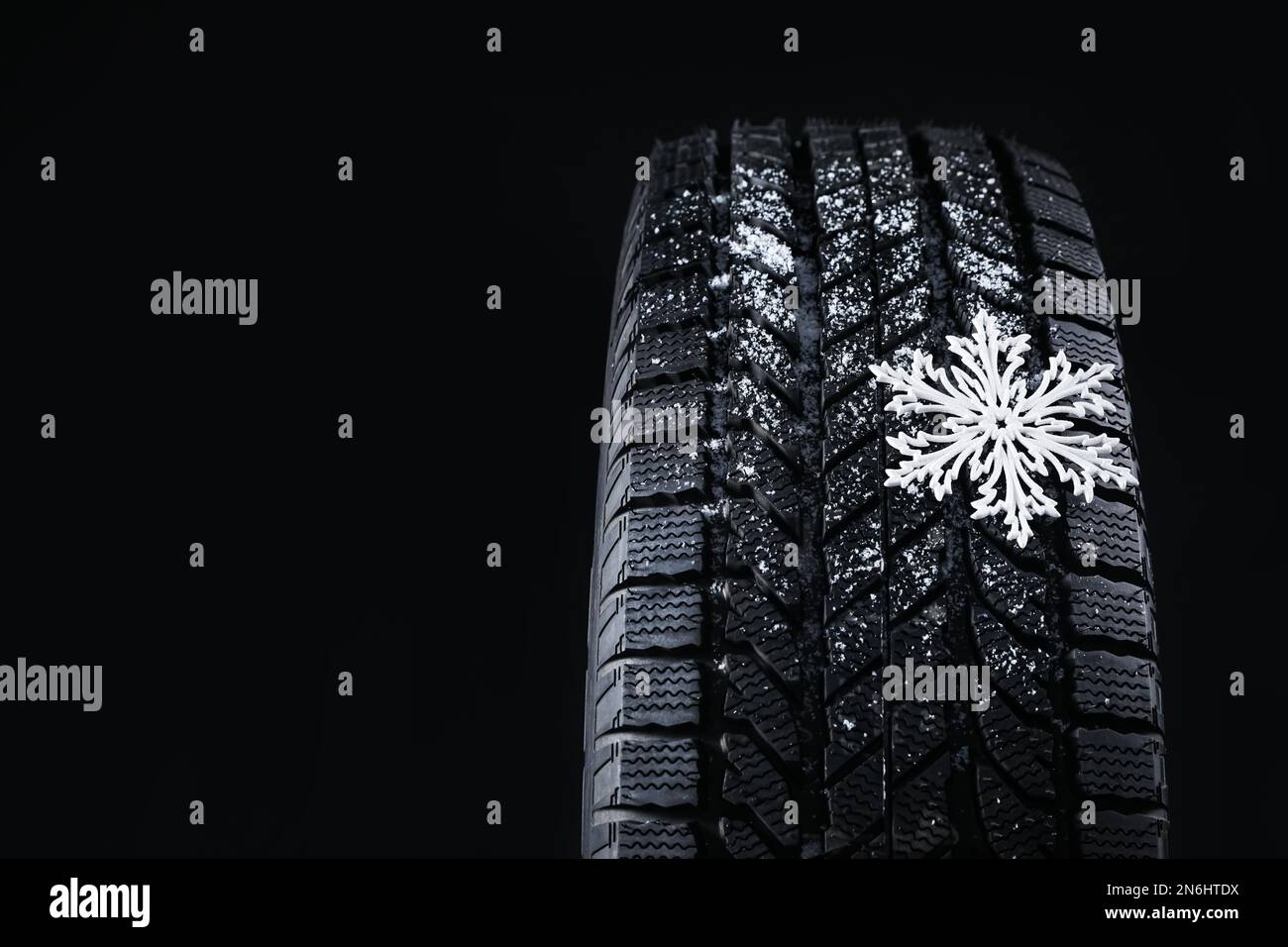 Winterreifen mit dekorativer Schneeflocke auf schwarzem Hintergrund, Nahaufnahme. Platz für Text Stockfoto