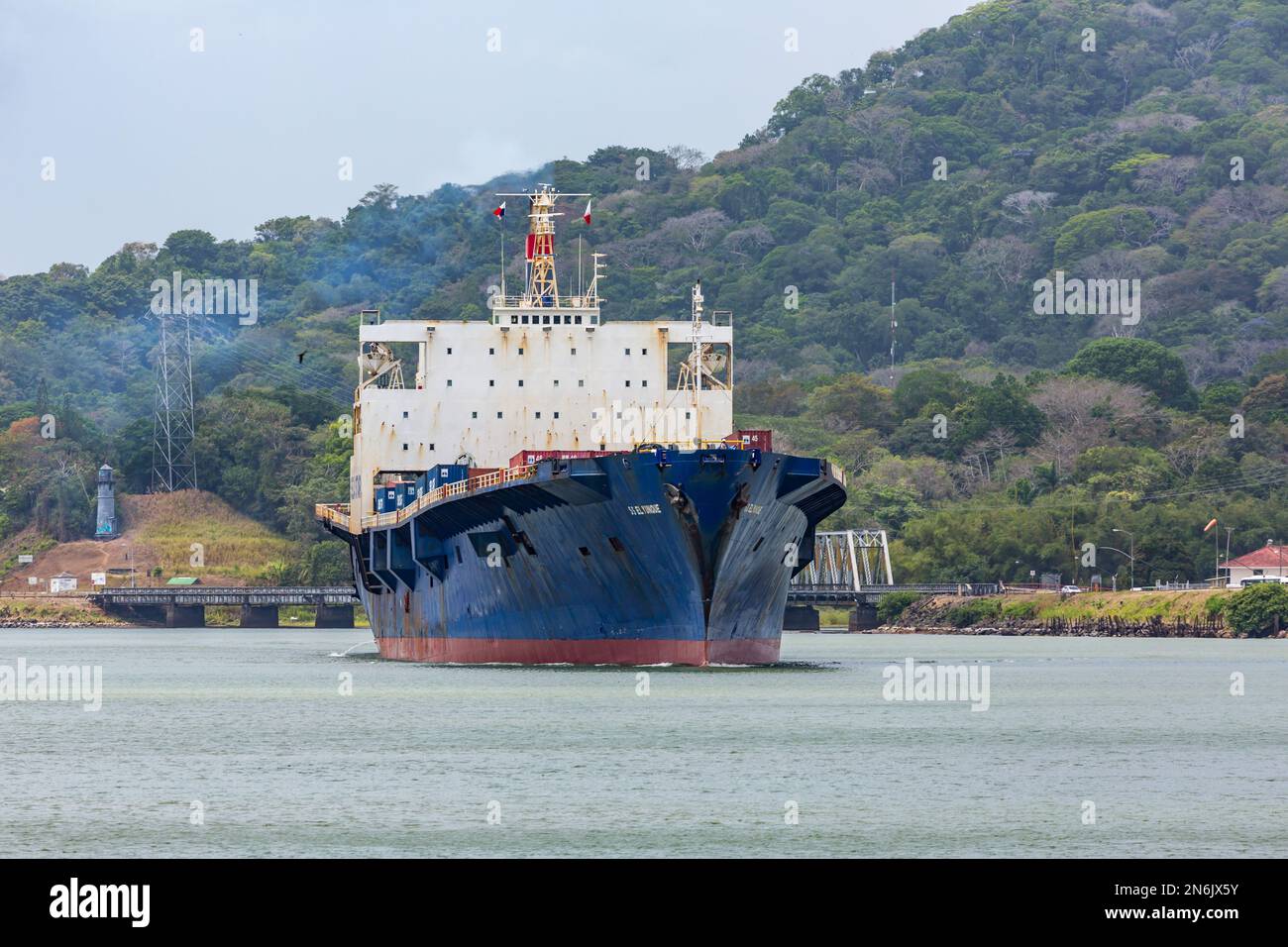 El Yunque, ein Containerschiff, bewegt sich in den schmalen Culebra-Schnitt bei Gamboa im Panamakanal. Die Gamboa-Brücke befindet sich auf der rechten Seite. Panama. Stockfoto
