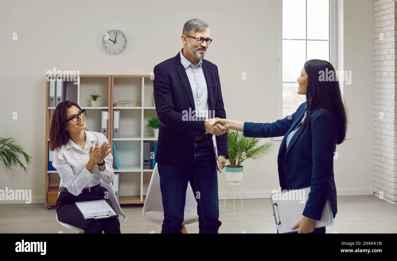 Lächelnder Geschäftsmann, der die Hand eines Kandidaten im Amt schüttelt Stockfoto
