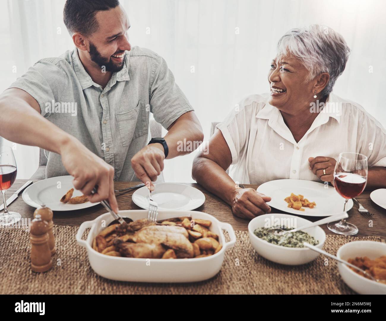 Liebe, Mutter und erwachsener Sohn schneiden Hühnchen, Veranstaltung und Unterhaltung mit Glück, Familie und Liebe zusammen. Glücklich, Mama und männliches Kind mit Essen, lächeln Stockfoto