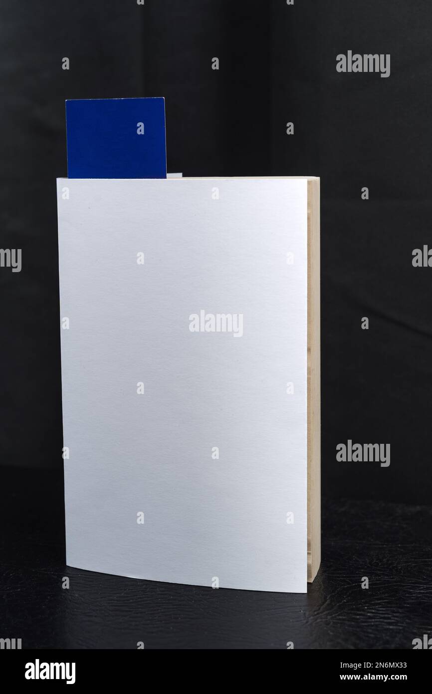 Leere weiße Buchumschlagsvorlage mit blauem Lesezeichen auf dem schwarzen Lautsprechergehäuse. Beschneidungspfad. Stockfoto