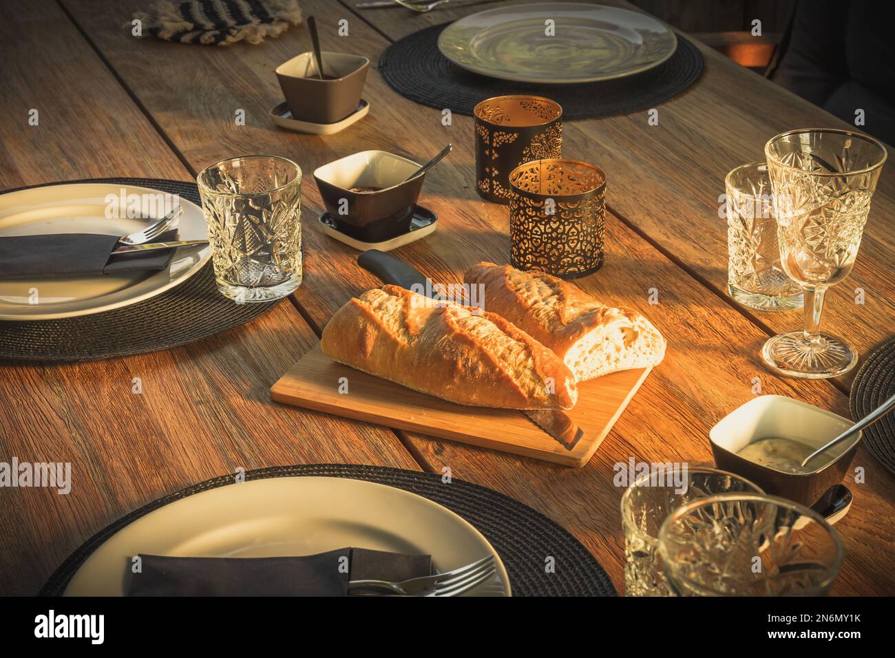 Liegender Gartentisch mit Baguette-Brot zum Abendessen in der Abendsonne Stockfoto
