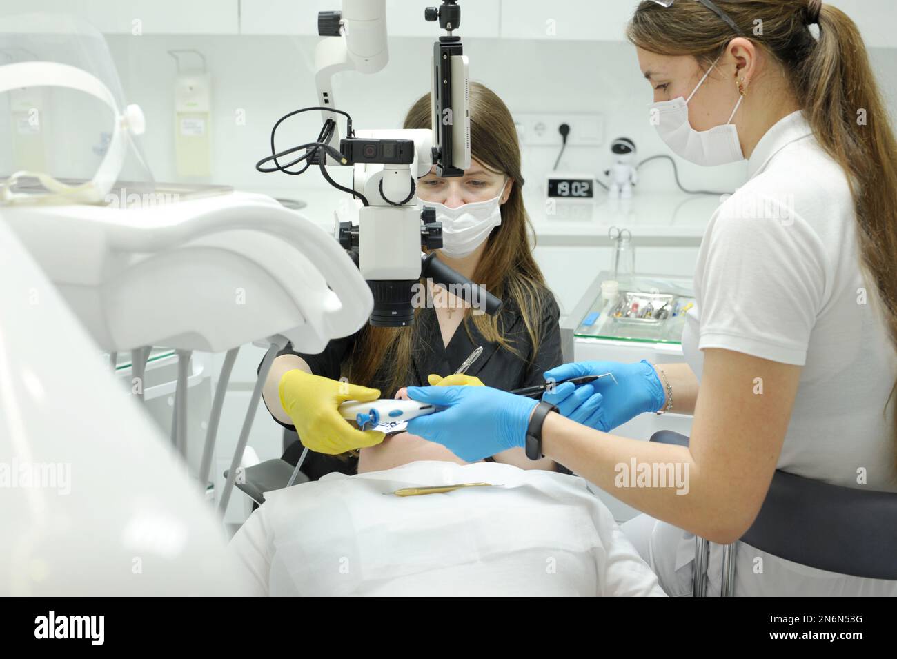 Moderne Wurzelfüllungsverfahren in der Zahnklinik mit dem Mikroskop andere Technik der Arztschwester hilft dem Patienten mit Zahnschmerzfüllungsprostheti Stockfoto