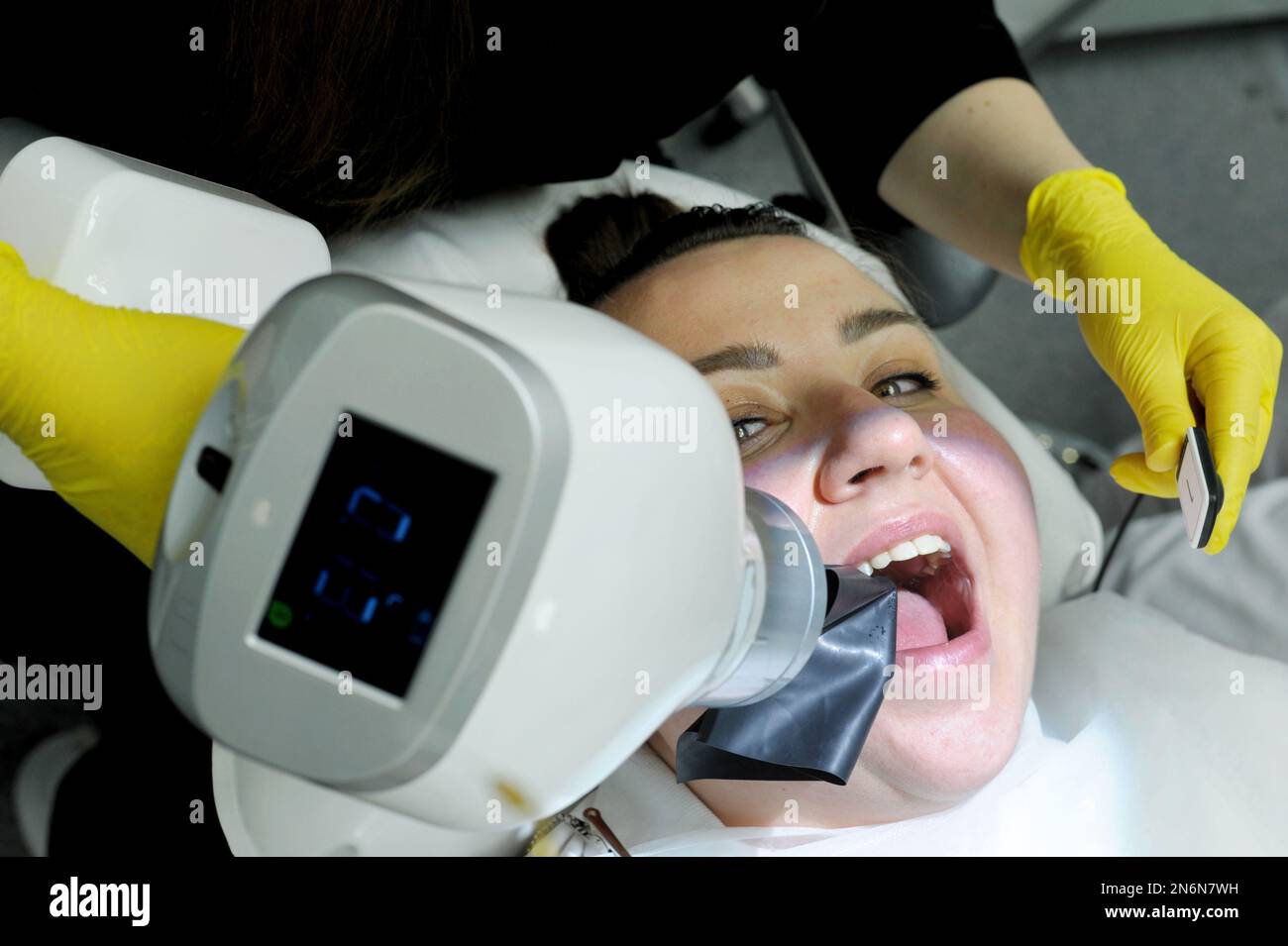 Neueste Technologie in der Zahnklinik mit Hilfe des neuen Röntgenscanners Frau wird aufgenommen Bild füllende Kanäle Frau lächelt hübsch auf Arzt gelbe Handschuhe und Stockfoto