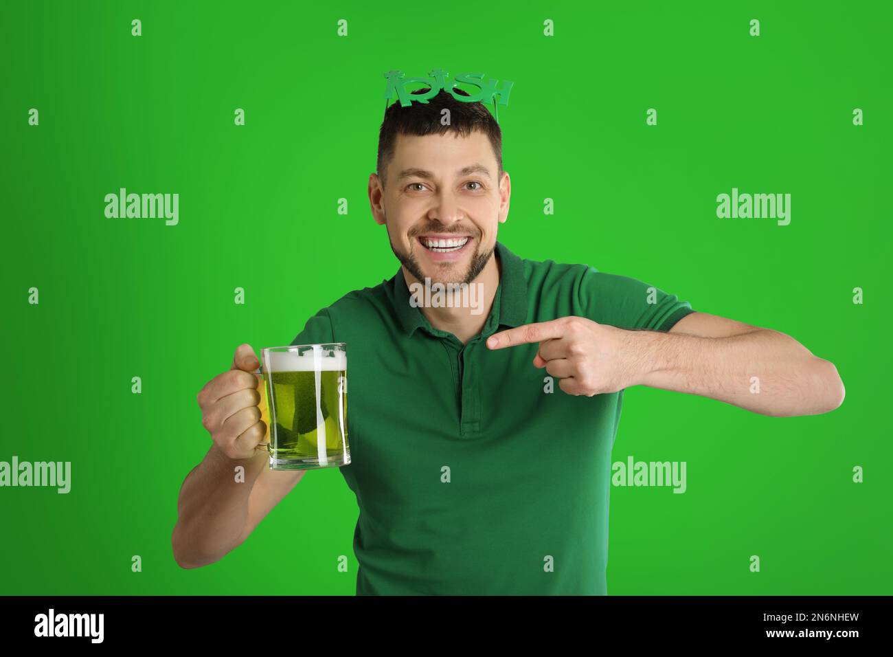 Glücklicher Mann in St. Patrick's Day Outfit mit Bier auf grünem Hintergrund Stockfoto