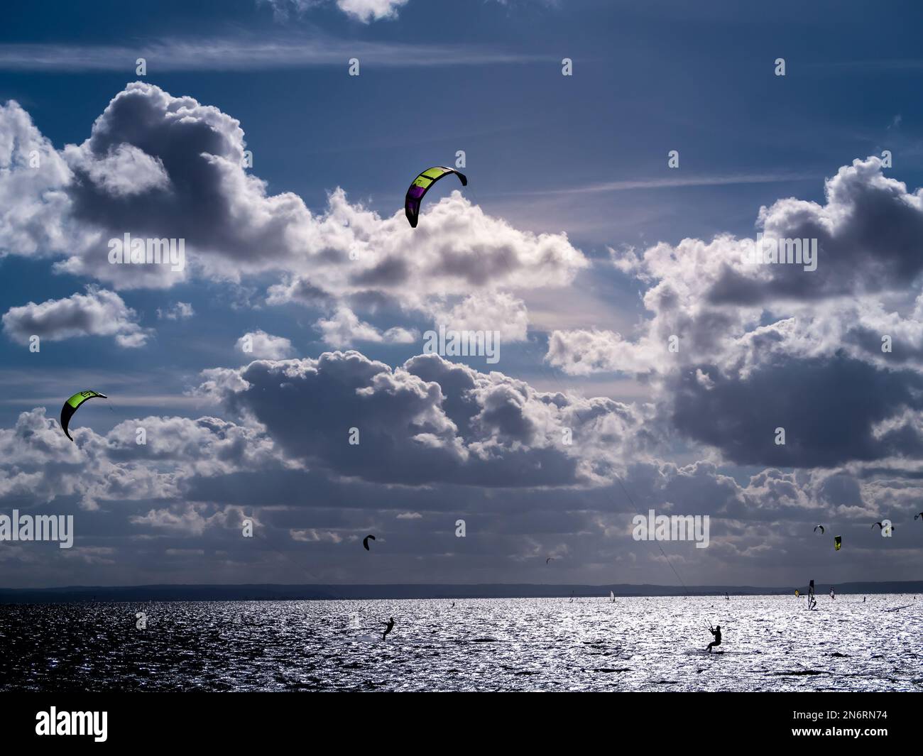 Silhouetten mit Hintergrundbeleuchtung von vielen Kitesurfern, die auf dem Meer surfen, Jastarnia, Polen Stockfoto