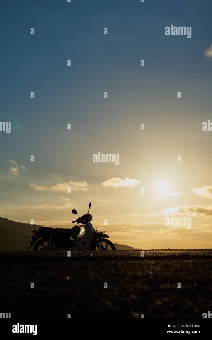 Eine Motorradsilhouette auf einer Bergstraße Stockfoto