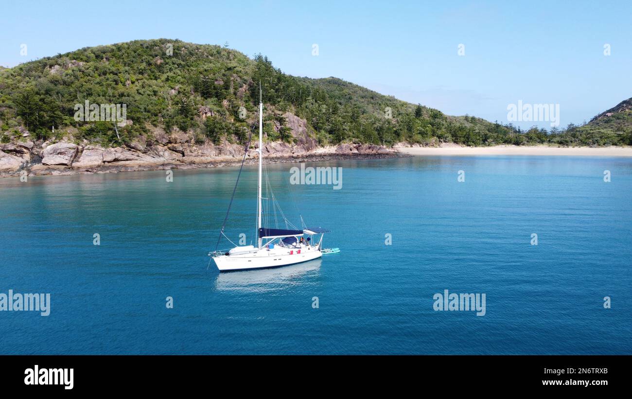 Segelboot ankert in einer Bucht mit einer tropischen Insel im Hintergrund. Whitsunday'S, Australien Stockfoto