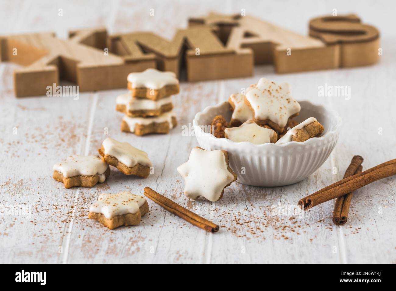 Weihnachtszimtsternkekse auf einem weißen Holztisch, im Hintergrund mit Holzbuchstaben Xmas Stockfoto