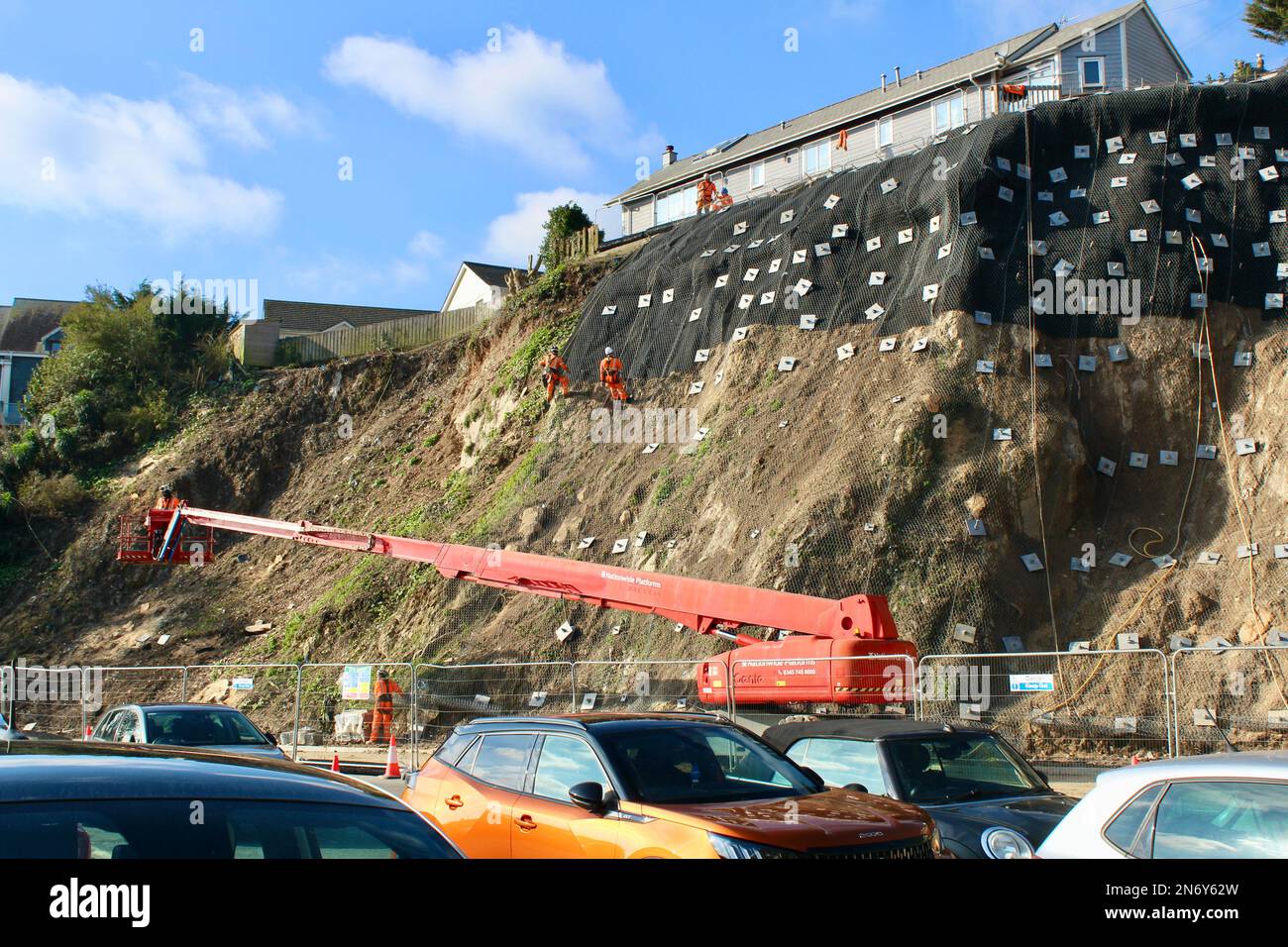 Klippenstabilisierungsarbeiten am Quarry Lane-Parkplatz in Falmouth, Cornwall, England. Die Abseilarbeiter führen die wesentlichen Arbeiten aus. Stockfoto