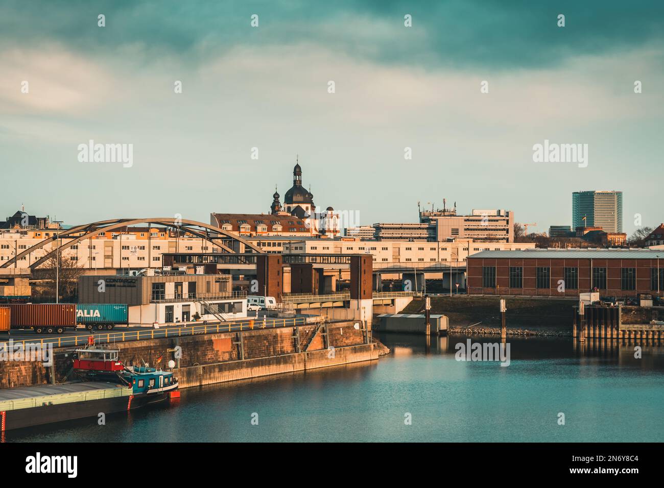 Mannheim, Deutschland - 26.03.2021: Hafengebiet mit Industrie, Wohngebäuden und Blick auf die Jesuitenkirche in wunderschönem Abendlicht Stockfoto