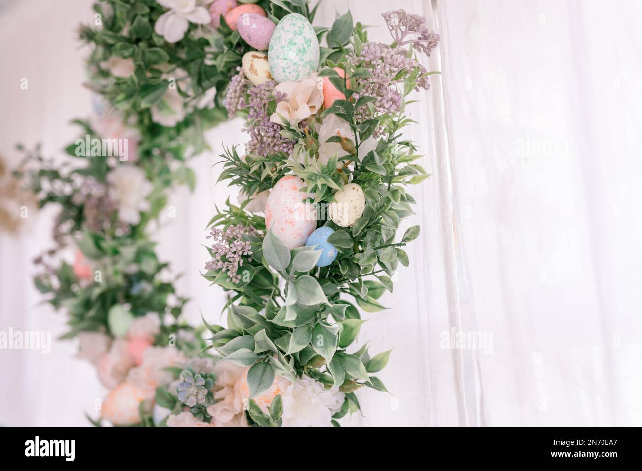 Frohe ostern- und Frühlingsferien. osterkranz mit Zweigen von Fliederbuschblüten und Blättern und dekorierten bunten Eiern in hellem Licht Stockfoto