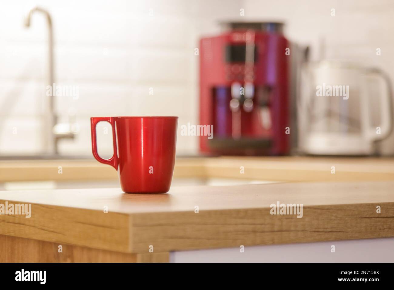 Eine einzelne rote Kaffeetasse auf der hölzernen Küchenablage Stockfoto