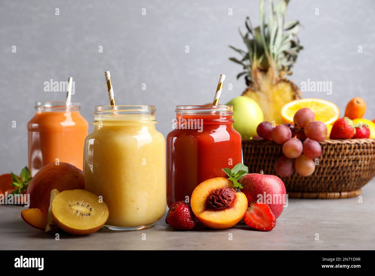 Köstliche Säfte und frische Zutaten auf dem grauen Tisch Stockfoto