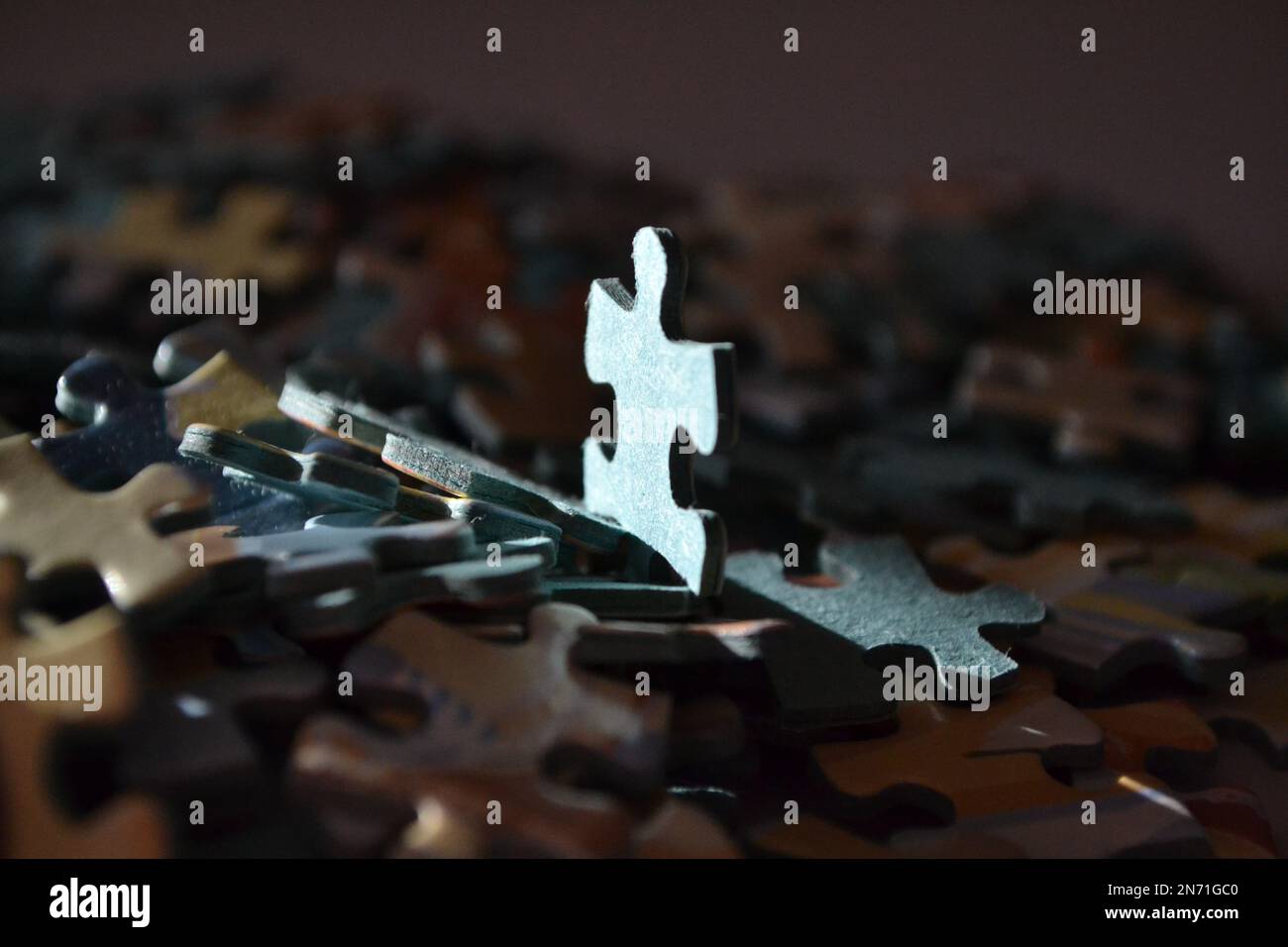 Puzzleteile in Einem Stapel Alle zusammen – ein Stück, das aufrecht steht und die Sonne auf der Rückseite glänzt. UK Stockfoto