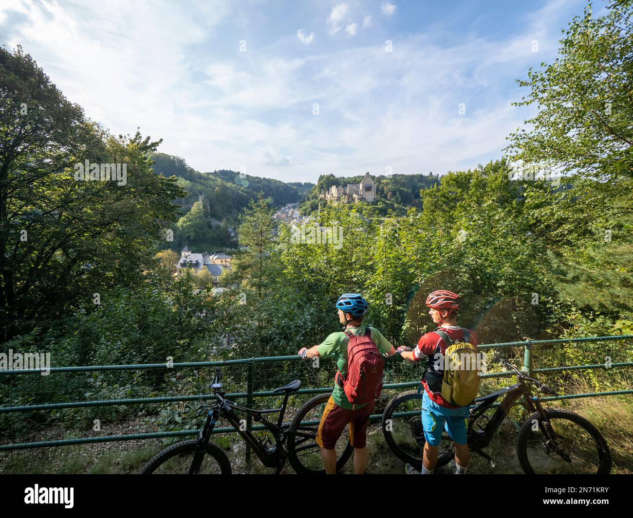 E-Mountainbiker über Larochette mit Blick auf Schloss Larochette und Schloss Fels in Larochette, Luxemburg. Die ersten Gebäude des Dorfes stammen aus dem 11. Jahrhundert und befinden sich auf einer Landzunge des luxemburgischen Sandsteins mit Blick auf das Tal des Weißen Ernz, einen Nebenfluss der Sure, ca. 150 Meter entfernt Stockfoto