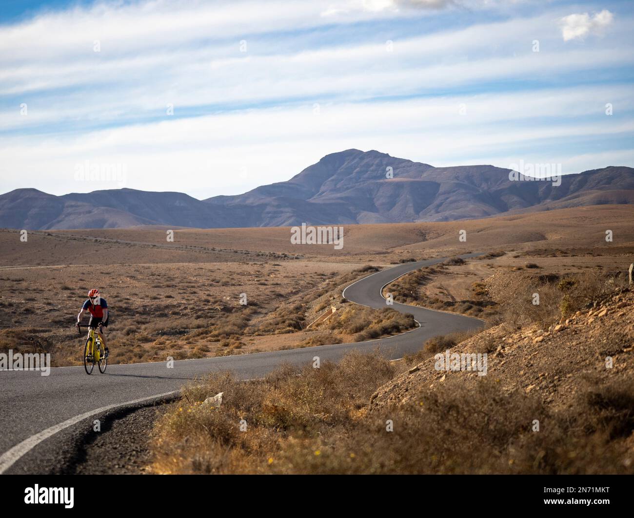 Radfahrer auf einer gewundenen Nebenstraße im zentralen Hügelland Fuerteventura bei Juan Gopar, Blick auf den Berg Montäa de Melindraga, Kanarische Inseln, Spanien Stockfoto