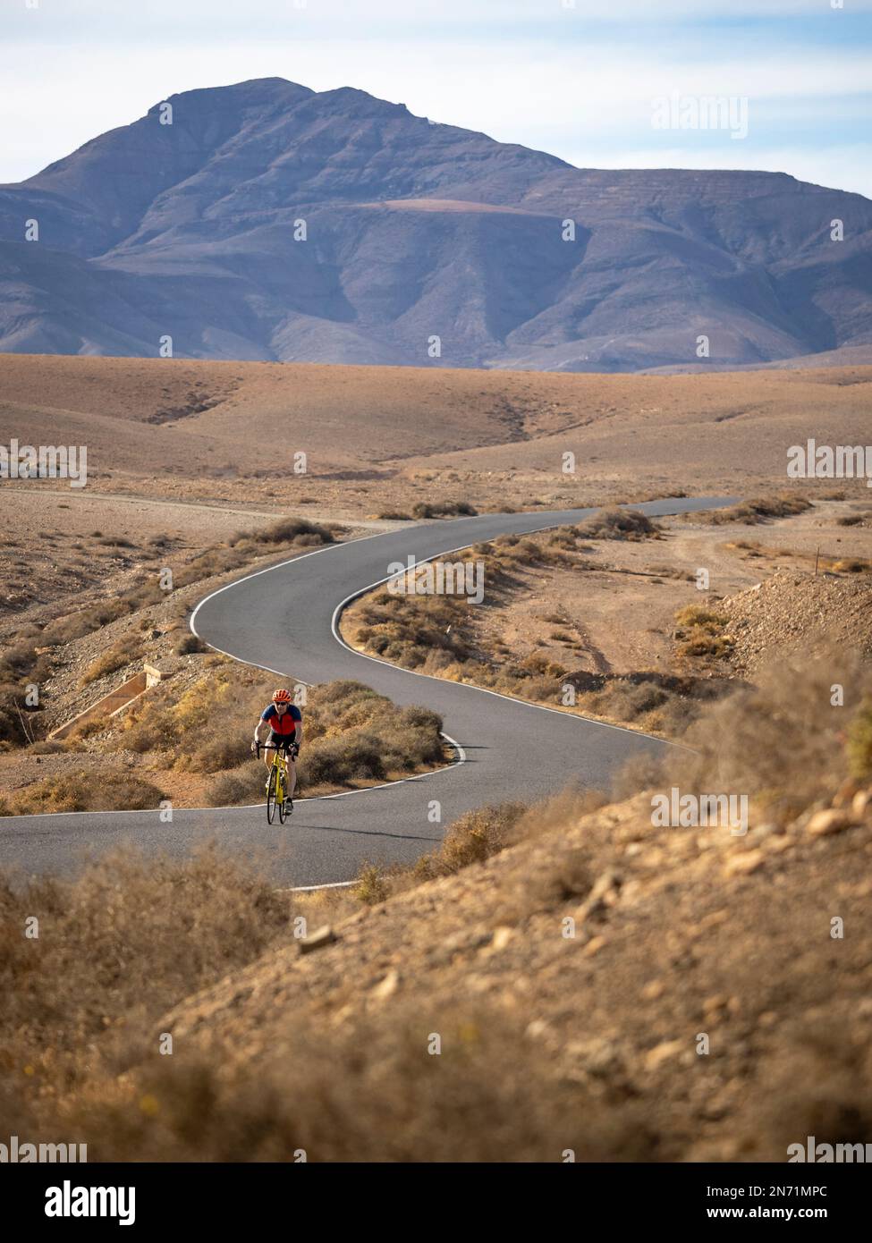 Radfahrer auf einer gewundenen Nebenstraße im zentralen Hügelland Fuerteventura bei Juan Gopar, Blick auf den Berg Montäa de Melindraga, Kanarische Inseln, Spanien Stockfoto