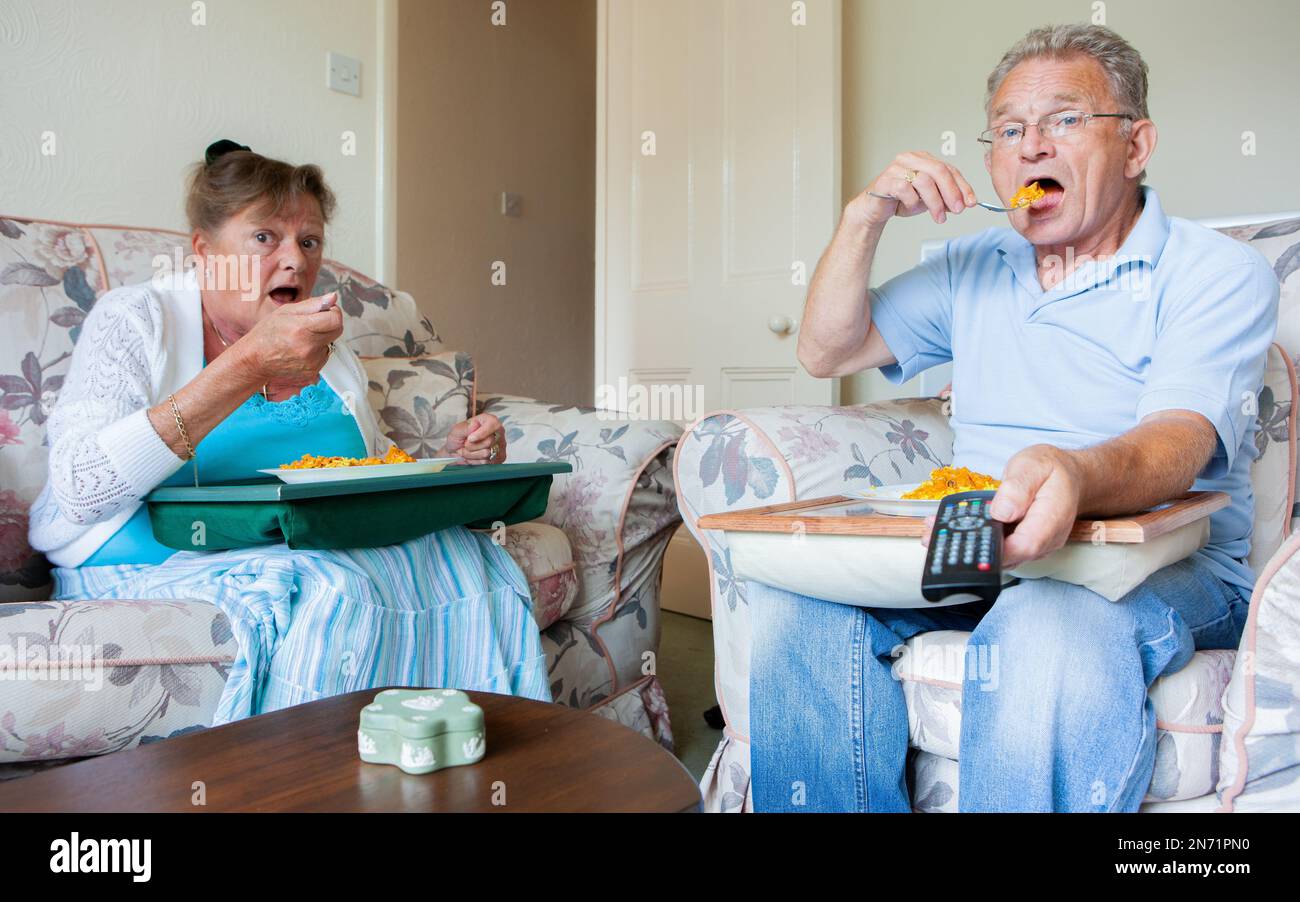 Ruhestand: TV-Dinner. Ein Seniorenpaar engagierte sich mehr mit ihrem Fernseher als miteinander. Aus einer Reihe von zugehörigen Bildern. Stockfoto