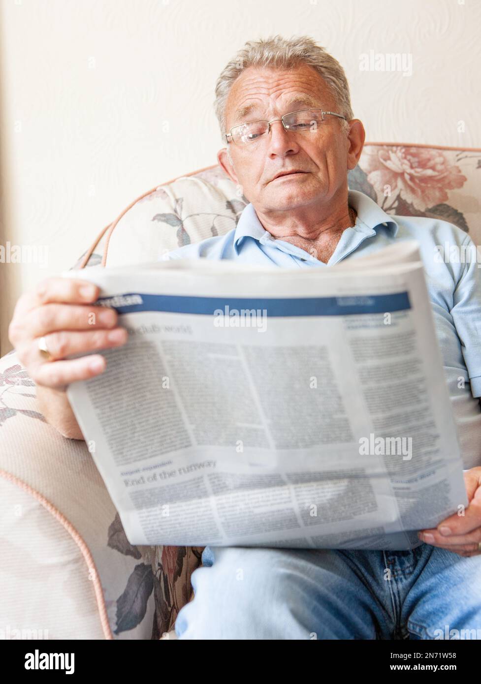 Ruhestand: Zeitung lesen. Ein Seniorenmensch hat sich in seine täglichen Nachrichten vertieft, während er über aktuelle Dinge auf dem Laufenden gehalten wird. Aus einer Reihe von zugehörigen Bildern. Stockfoto